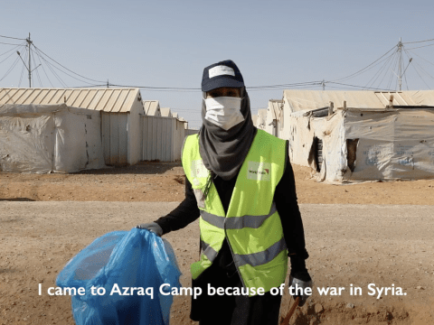 a teen stands outside a refugee camp in a high visibility vest